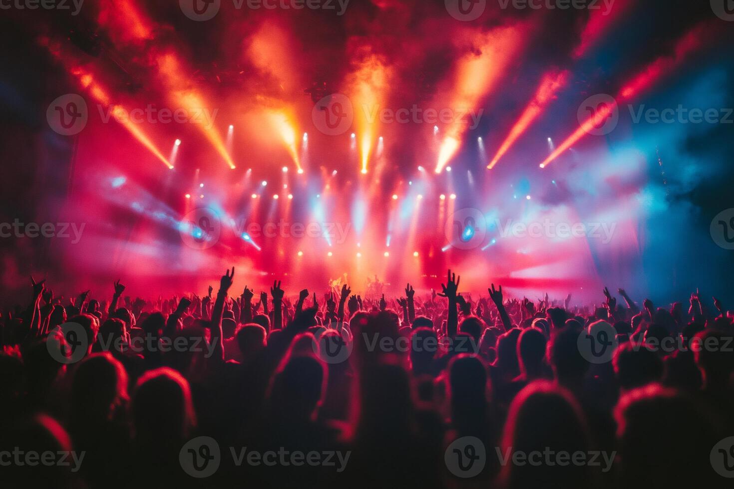 Crowd cheering and raising hands at illuminated concert with red and blue lights photo
