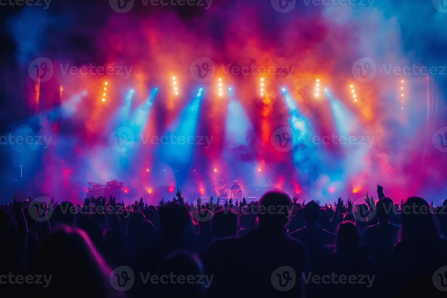 Crowd cheering and raising hands at music concert with colorful stage lights and smoke photo