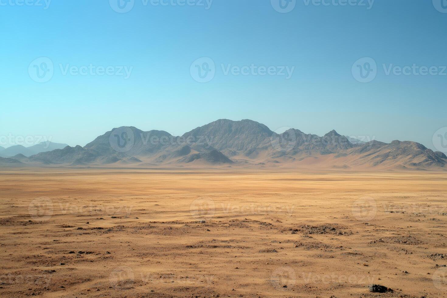Vast desert landscape stretching towards majestic mountains under blue sky photo