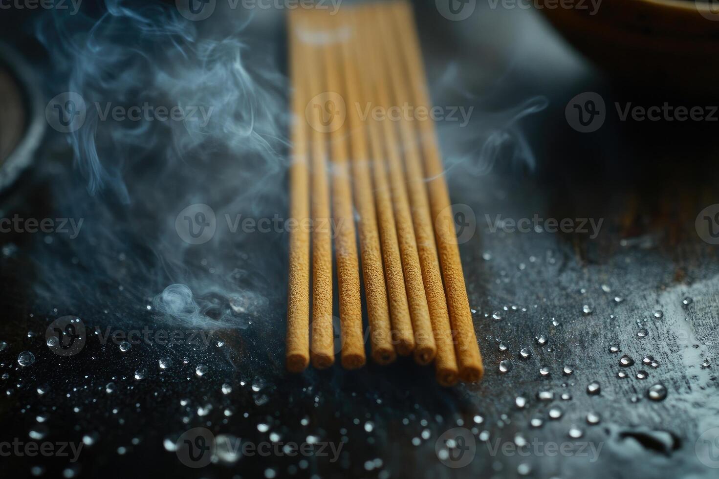 Aromatic incense sticks releasing smoke on wet stone surface photo