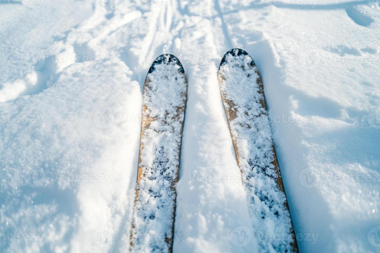 Skier looking down at skis on freshly groomed snow with mountains in background photo