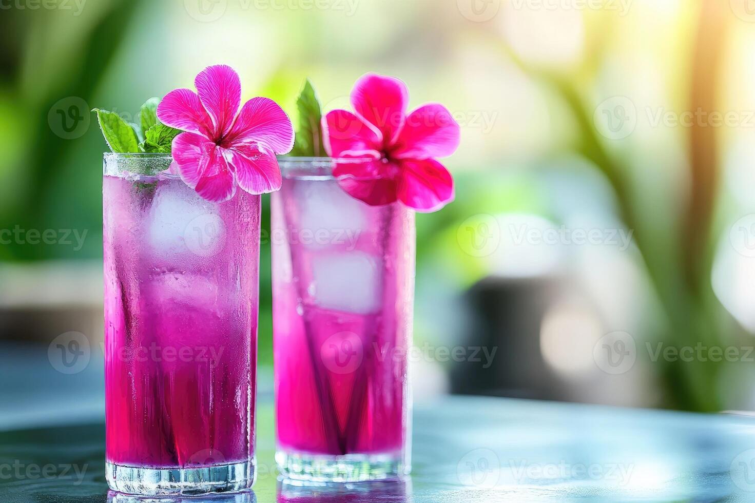 Two pink cocktails with ice cubes and flowers are standing on a table on a sunny summer day photo