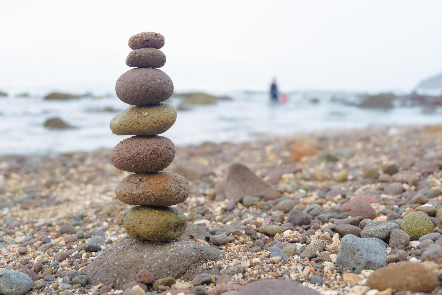 A carefully balanced stack of smooth pebbles on a rocky beach, symbolizing harmony, mindfulness, and stability. photo