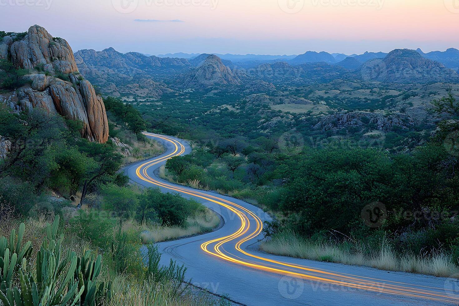 Scenic Sunset Over Curving Mountain Road with Light Trails in Serene Landscape photo