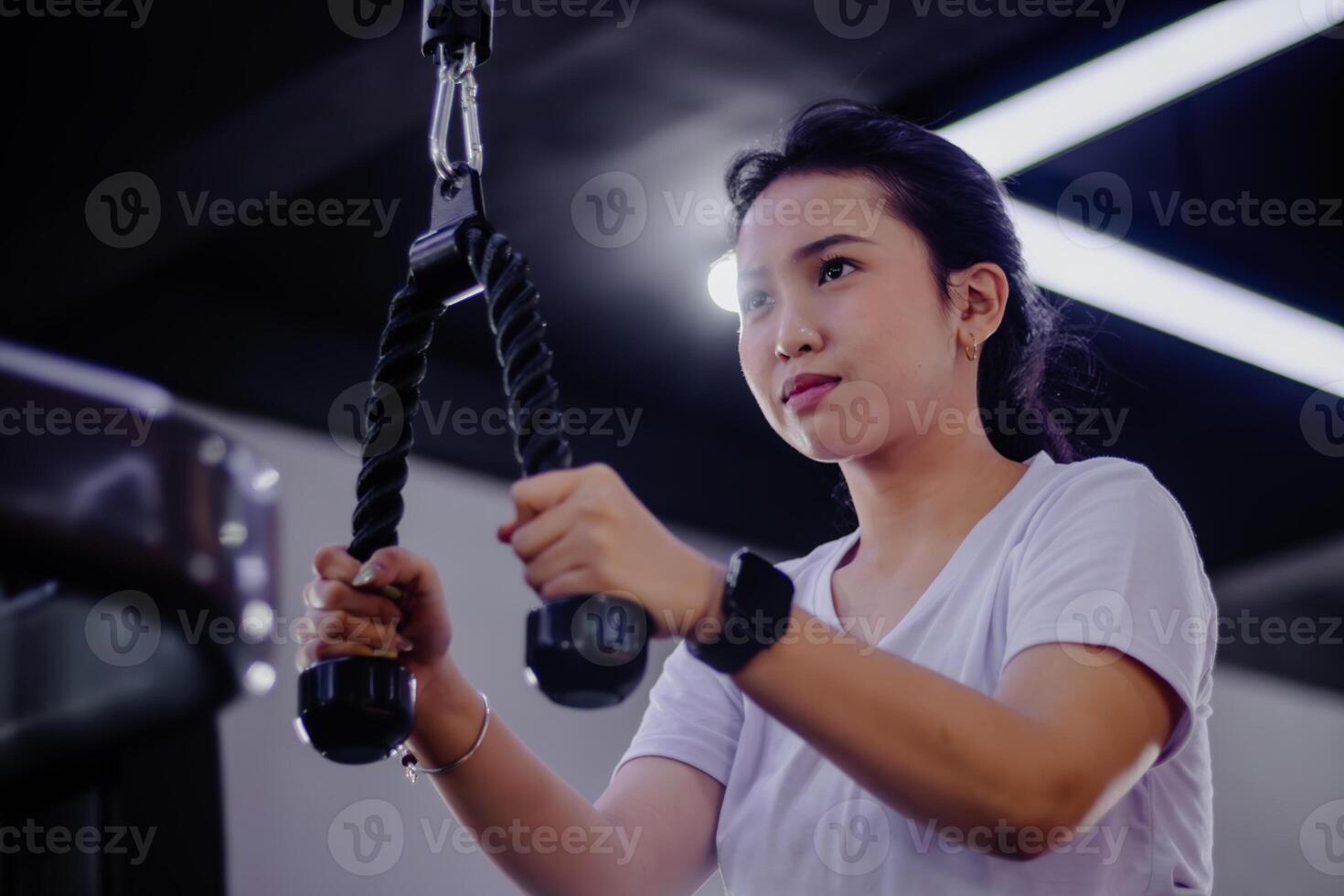 Asian woman strengthening triceps with a cable rope in fitness c photo