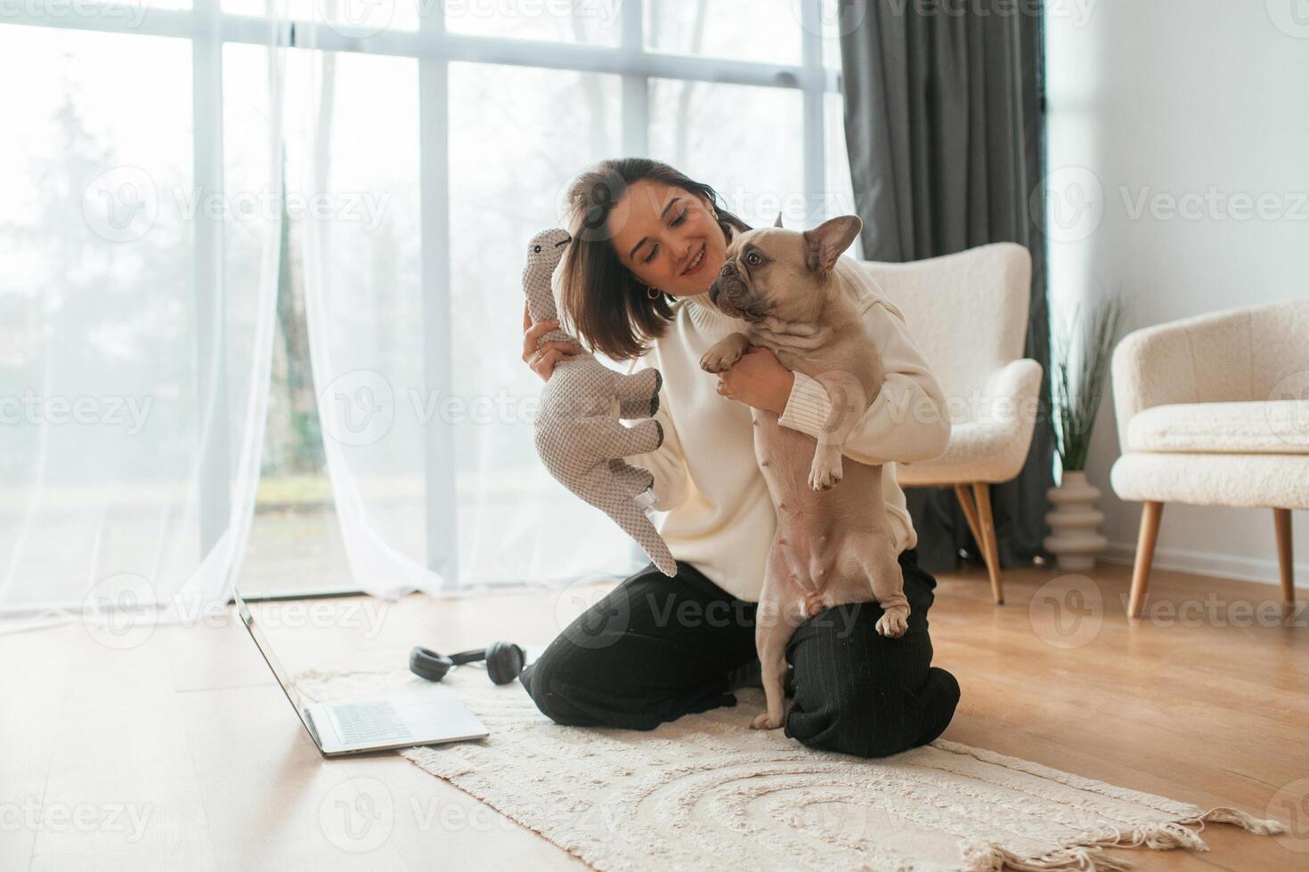 With toy, in hand. Young woman is with her pug dog at home photo