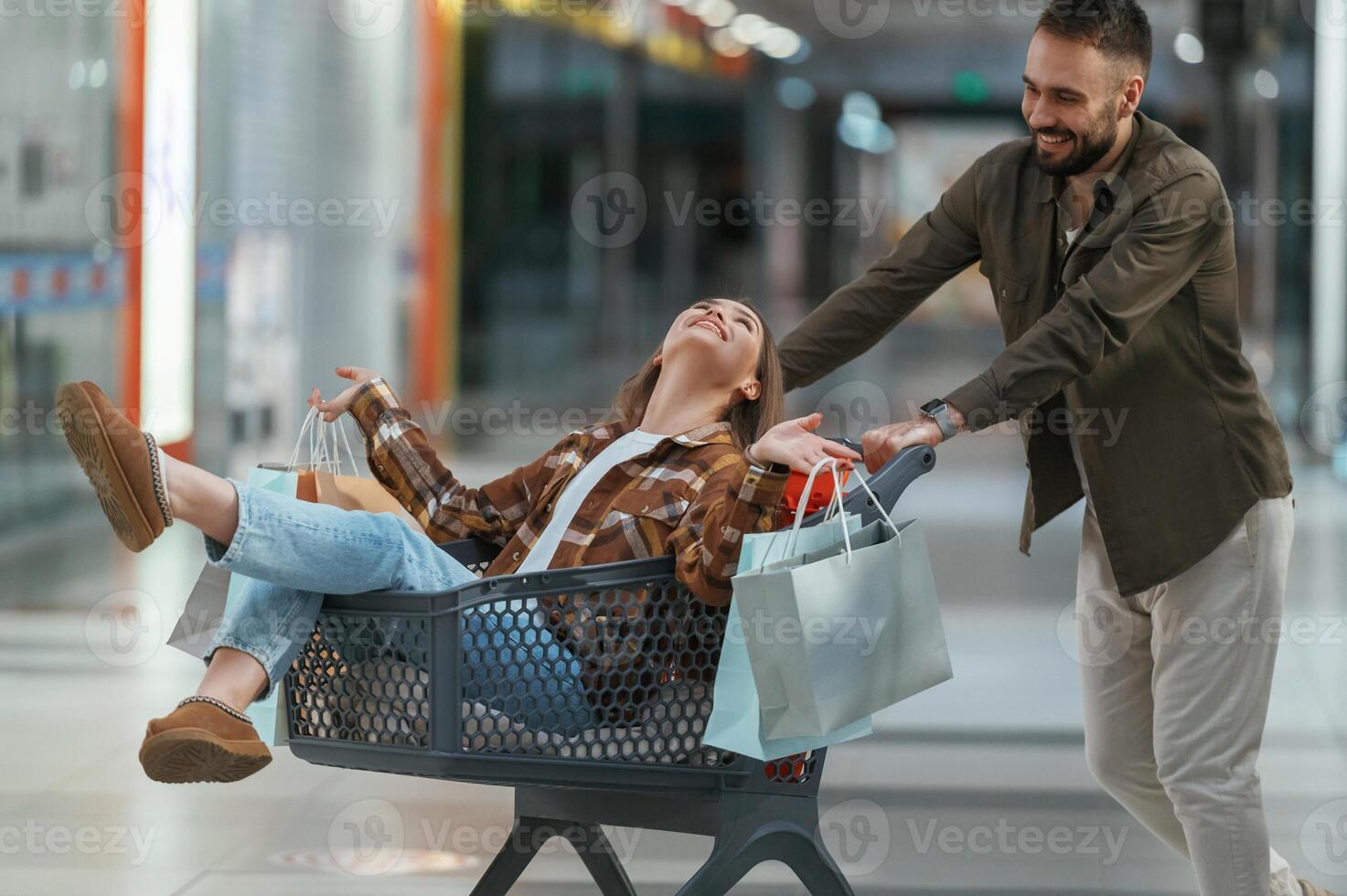 Riding in a ,shopping cart,,. Young couple are in supermarket together photo