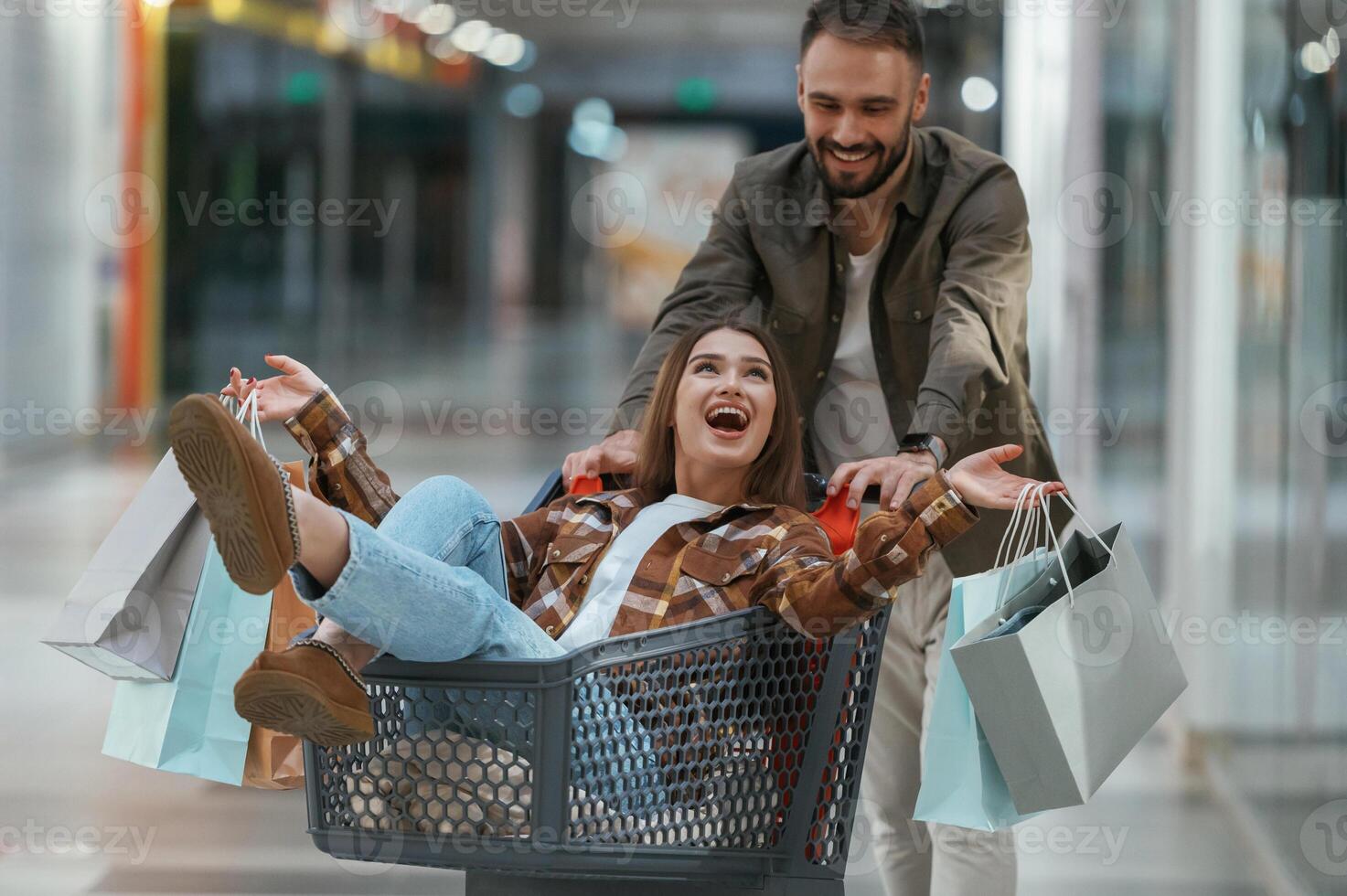 Riding in, a ,shopping cart. Young couple are in supermarket together photo