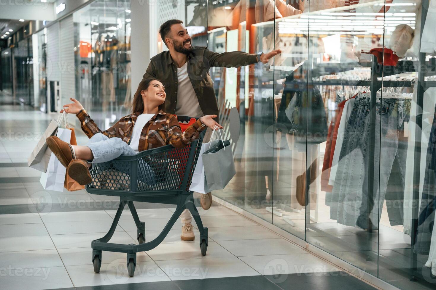 Cheerful,, riding in the cart. Young couple are in supermarket together photo