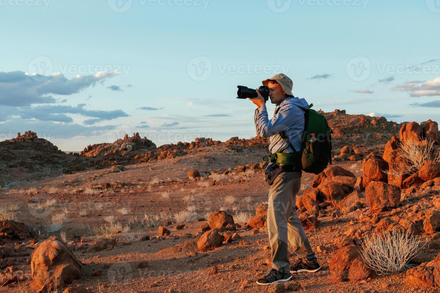 Using camera. Male tourist in casual ,clothes is in the deserts of Africa, Namibia photo
