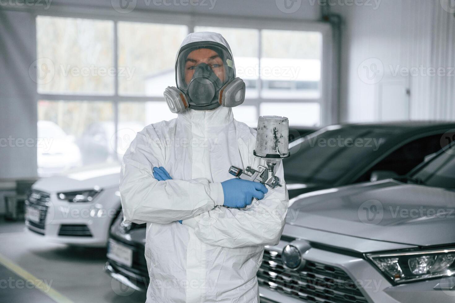 Customer ,,service. Man is standing and ,holding spray gun with paint for automobile photo