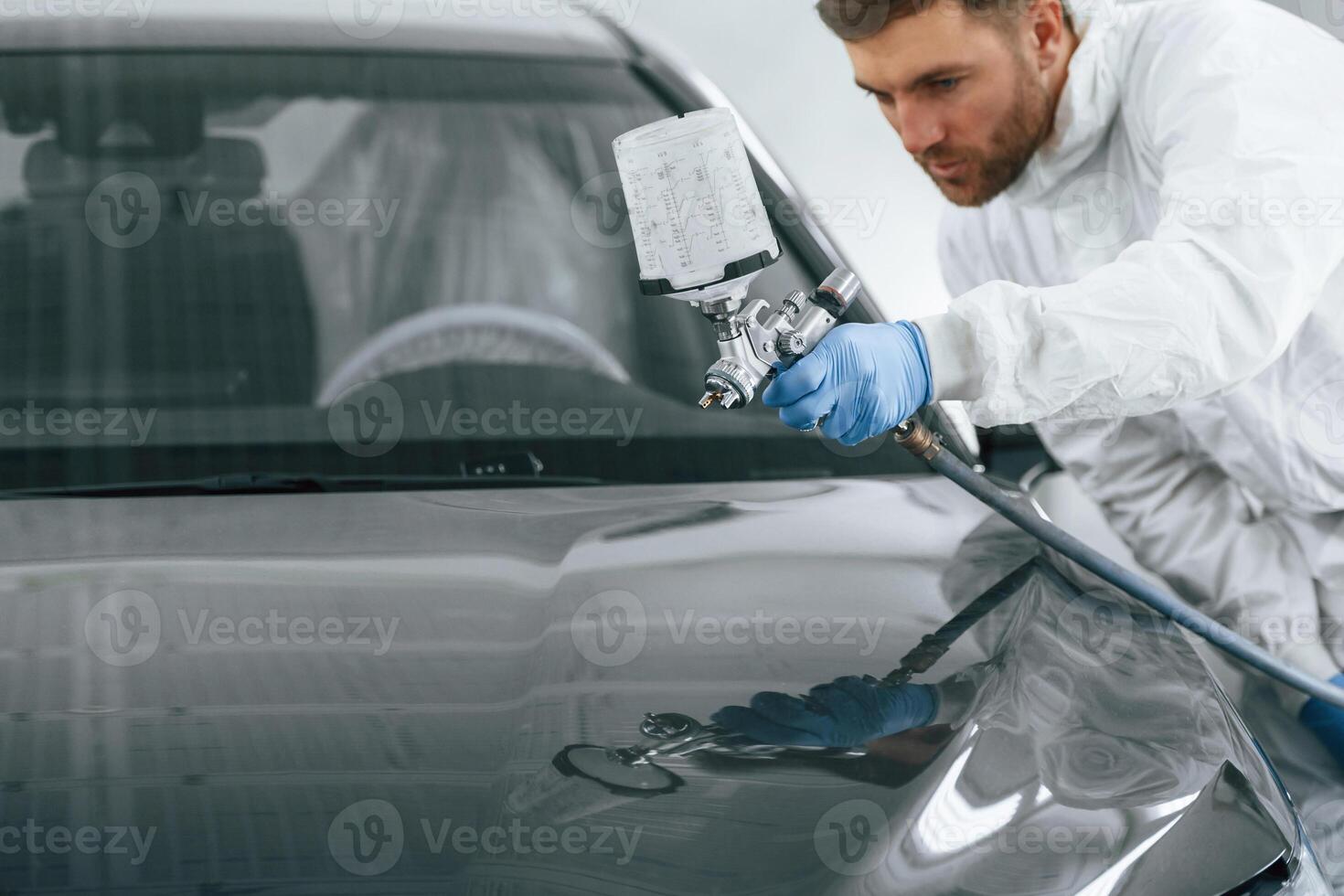 Man is painting a car by using spray guy. photo