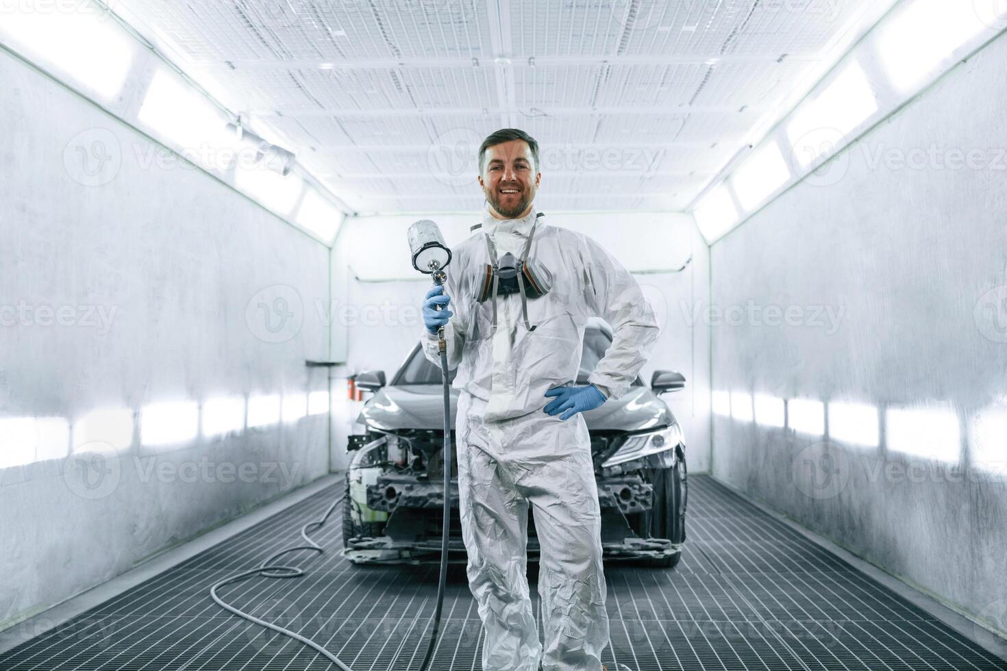 Man is standing and holding ,spray, gun with paint for automobile photo