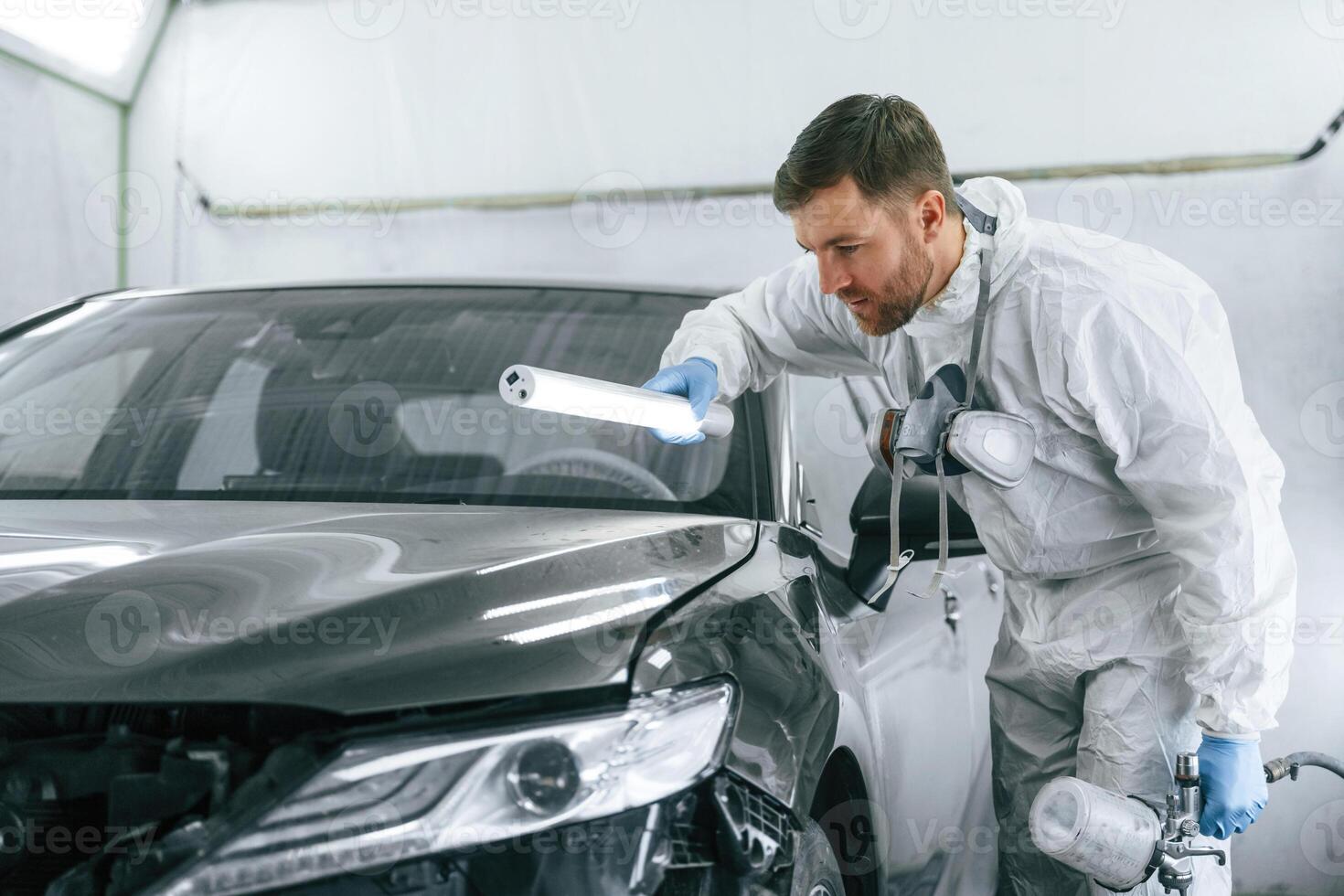 Front part, of ,,the automobile. Garage worker is holding lighting and checking surface of the car photo