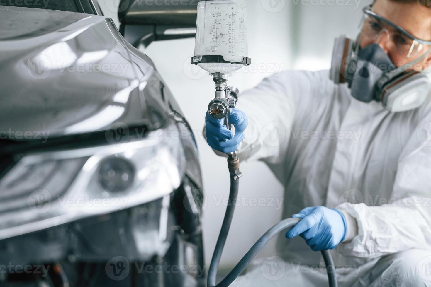 Man is painting ,a car by using spray guy photo