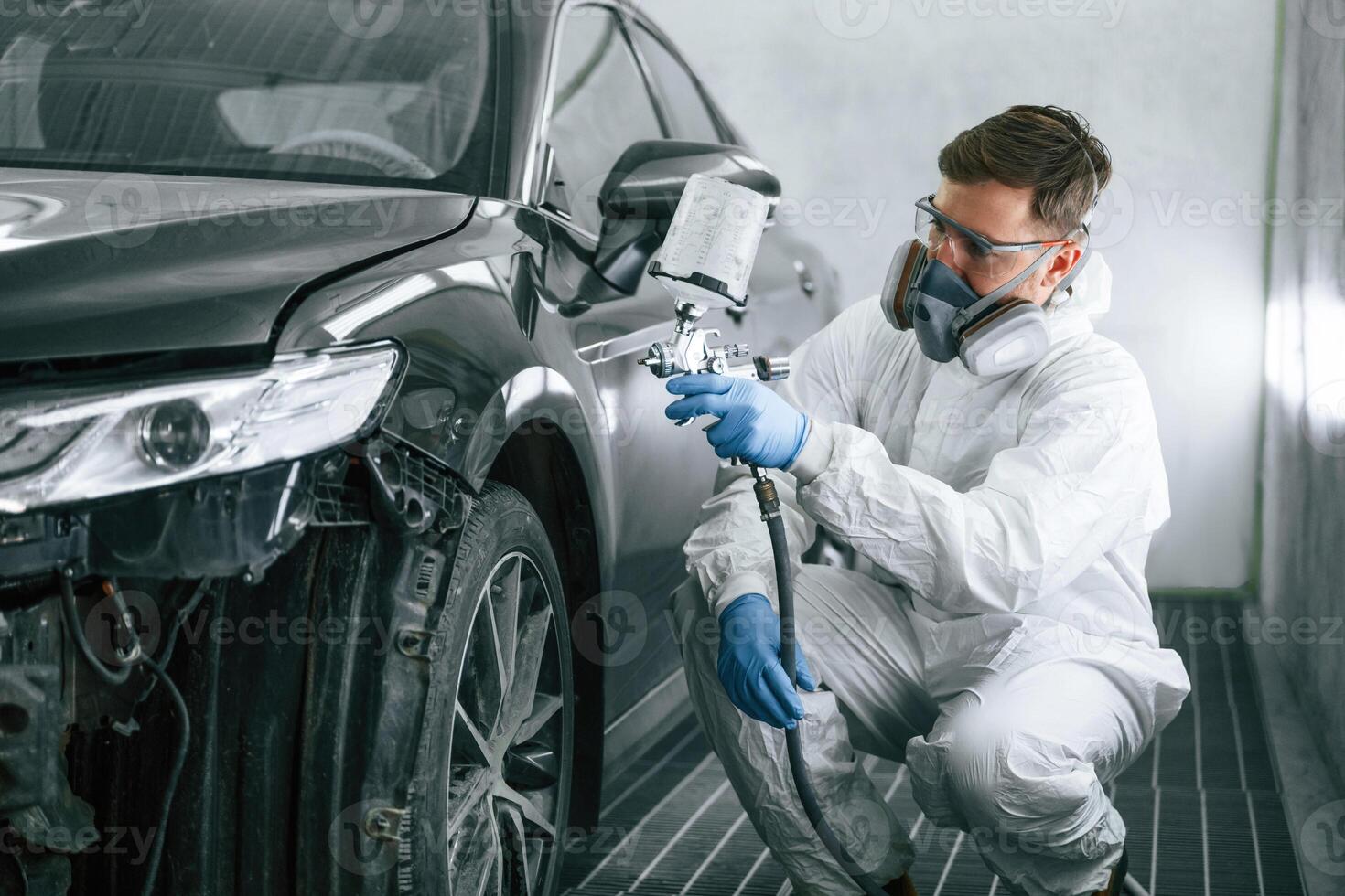 Professional, worker. Man,, is painting a car by using spray guy photo