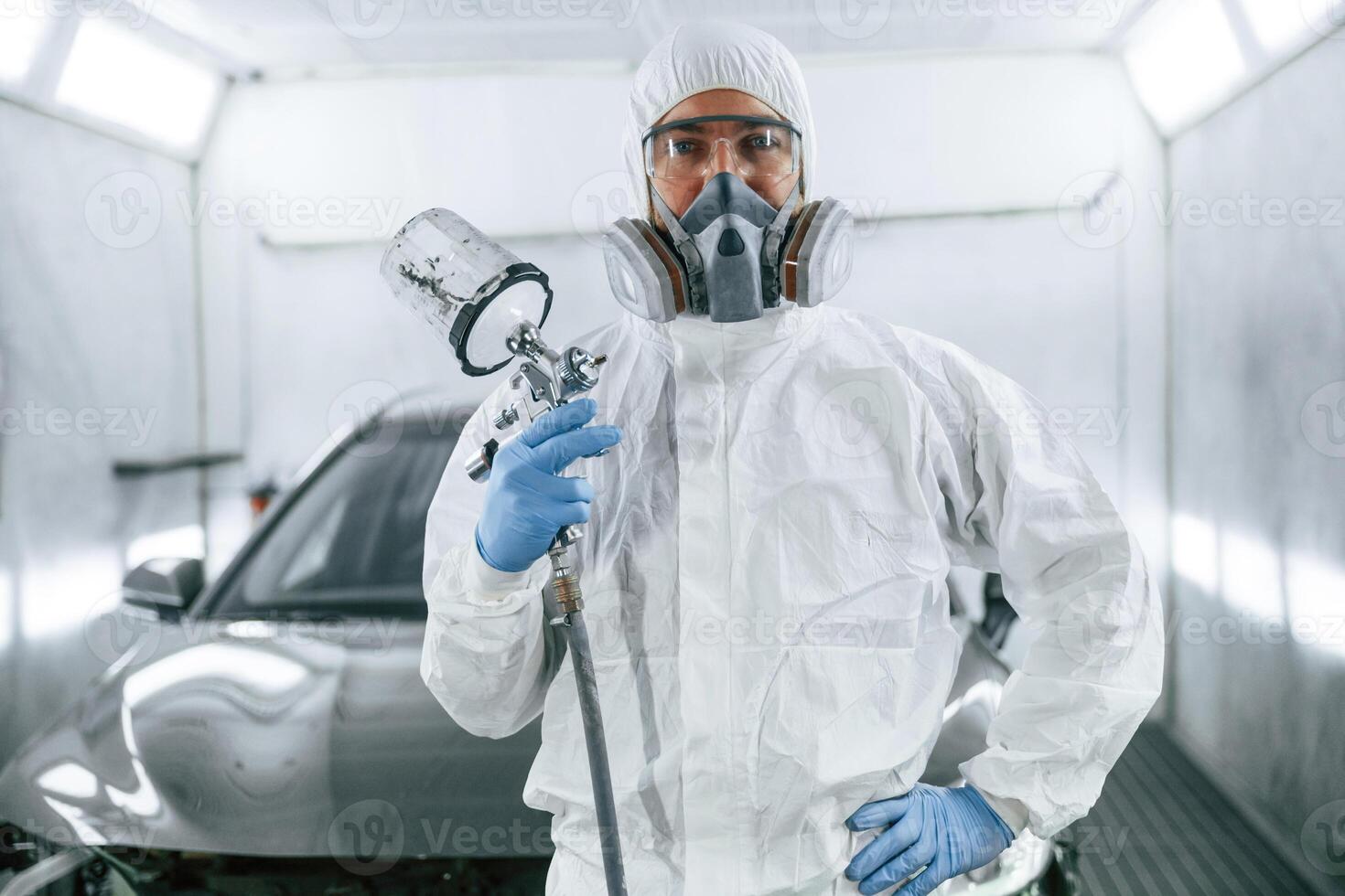 Customer ,service. Man is standing and holding spray gun with paint for automobile photo
