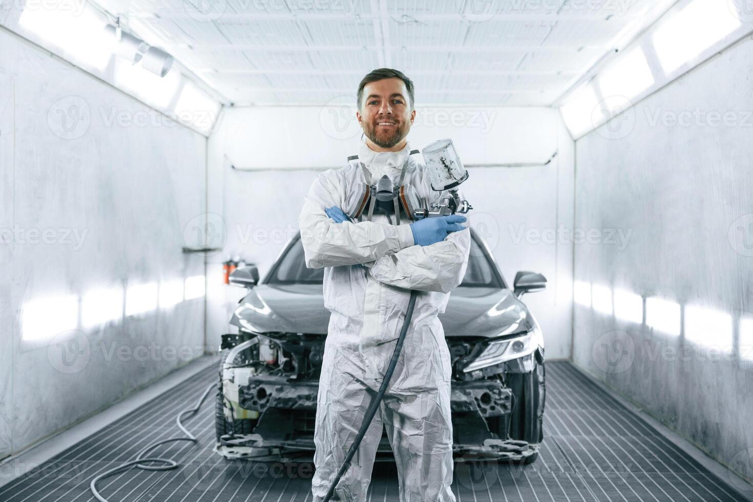 Man,, is standing and holding spray gun with paint for automobile photo