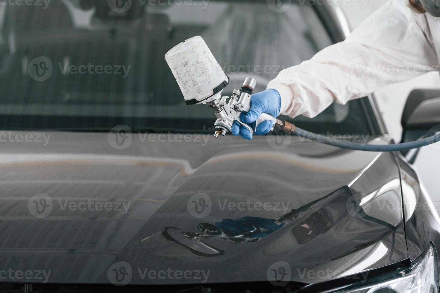 Close, up view of man that is painting a car by using spray guy photo