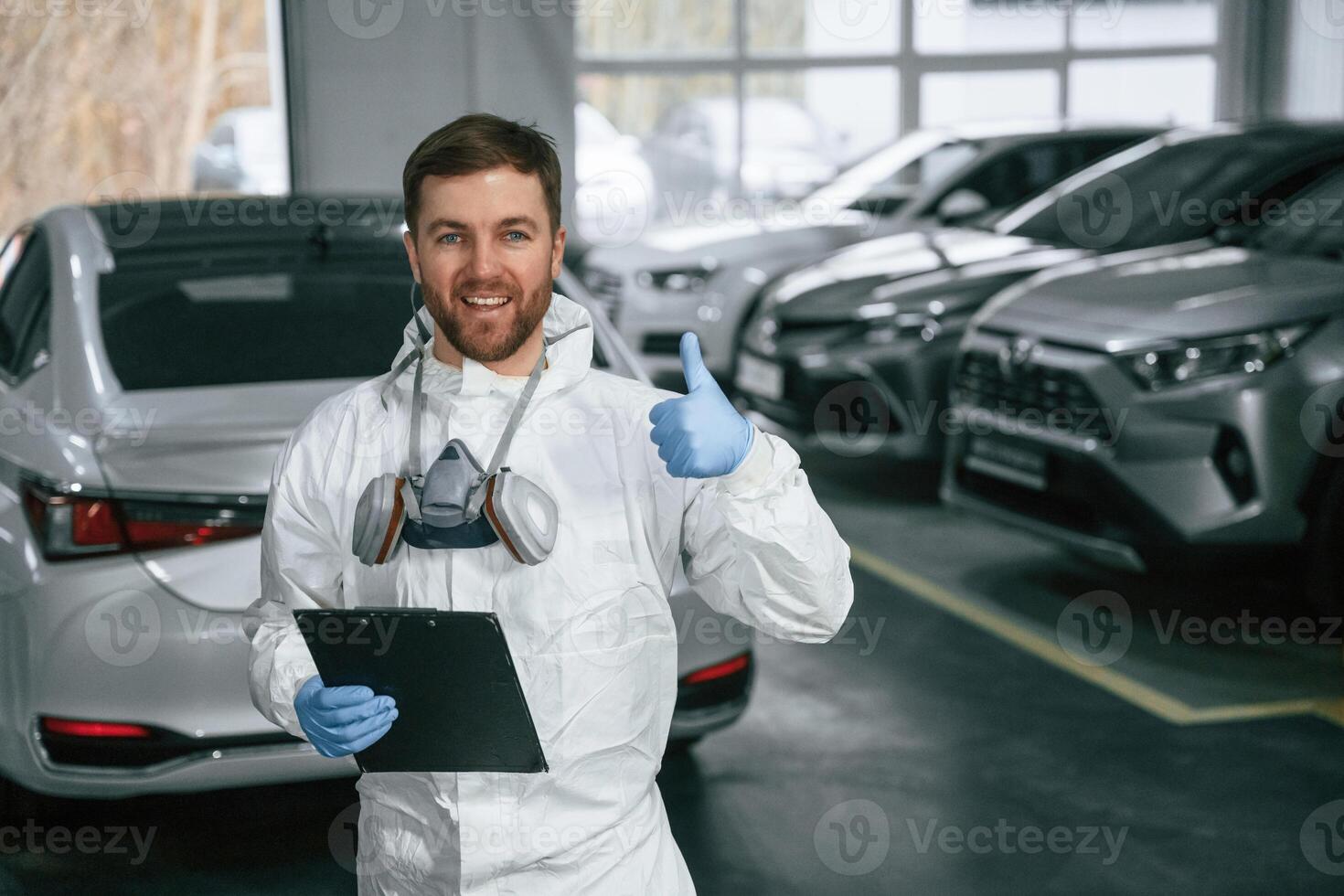 Portrait of car painter that is standing in the garage with ,,documents in hands photo
