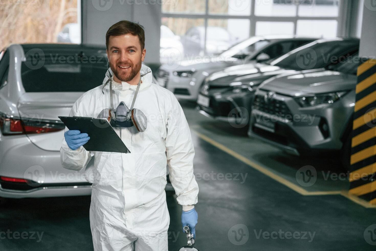 Positive ,facial ,expression. Car painter is standing in the garage with documents in hands photo