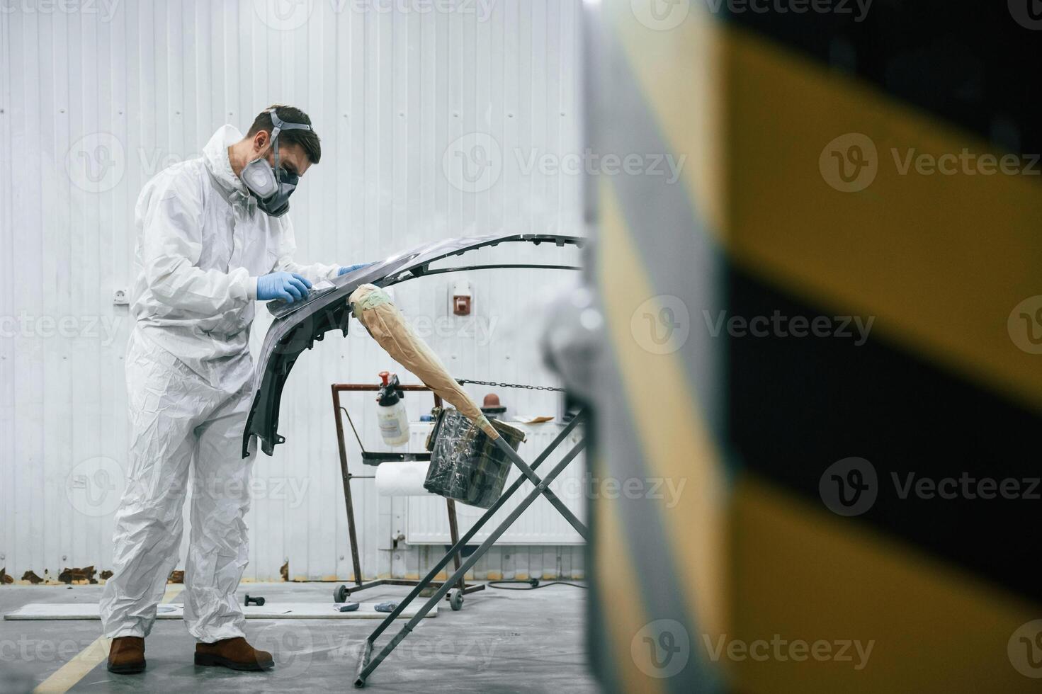 Side view. Repairman is, working with ,carcass of the car in the garage photo