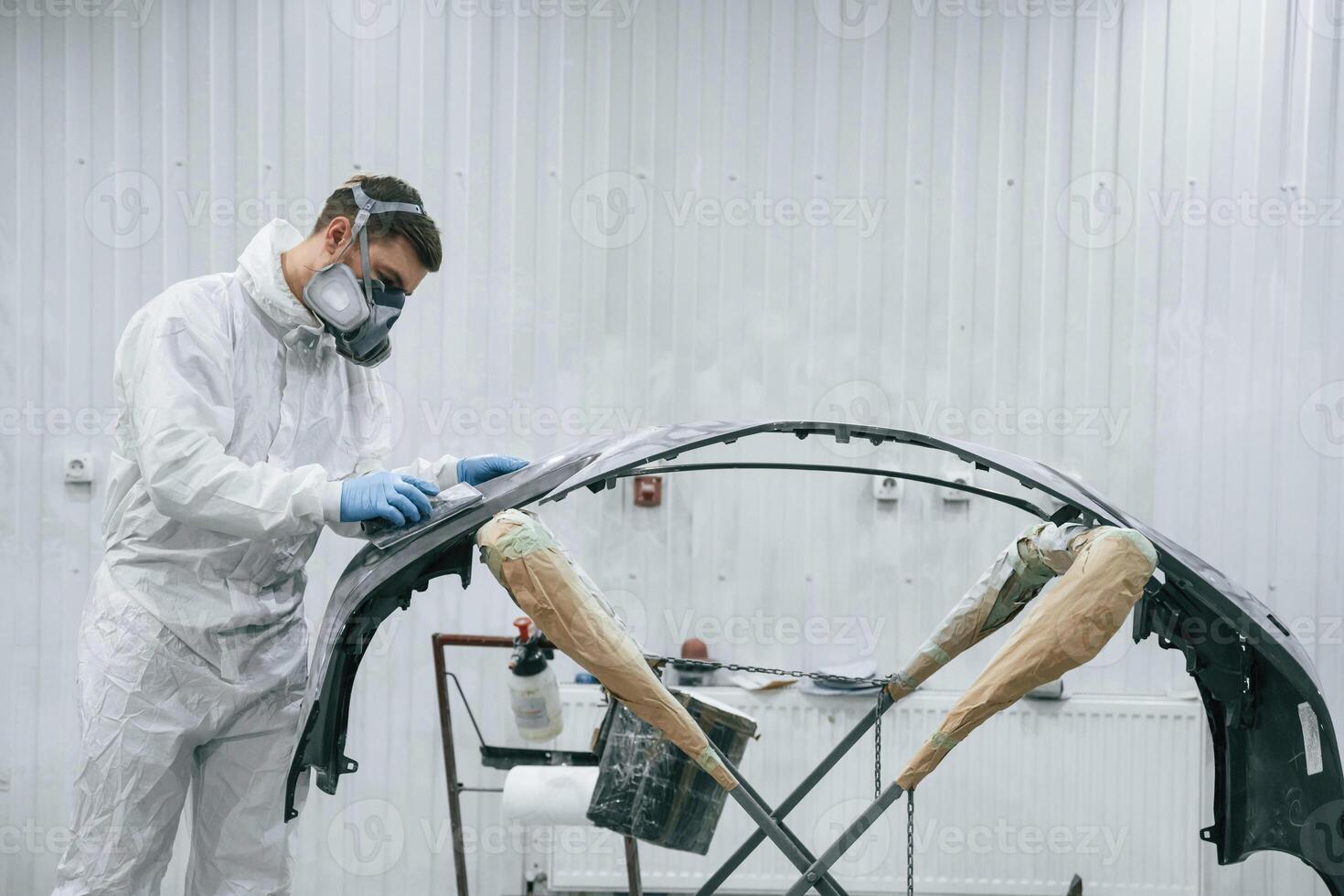 Unfinished part. Repairman ,,is working, with carcass of the car in the garage photo
