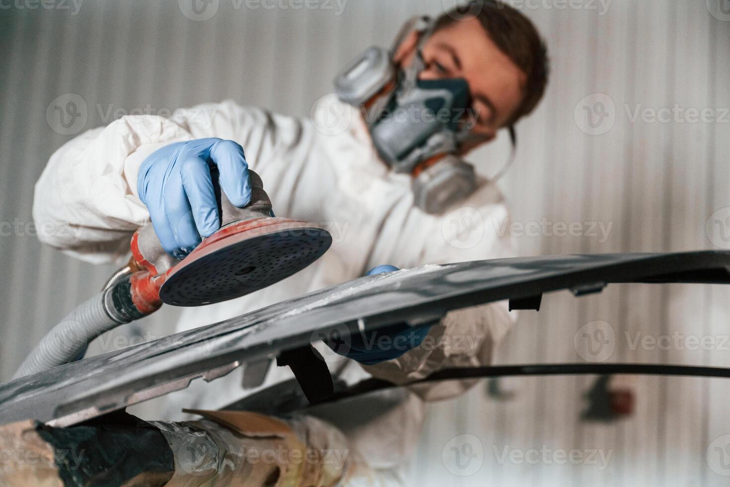 Polishing ,the, surface. Repairman is working with carcass of the car in the garage photo