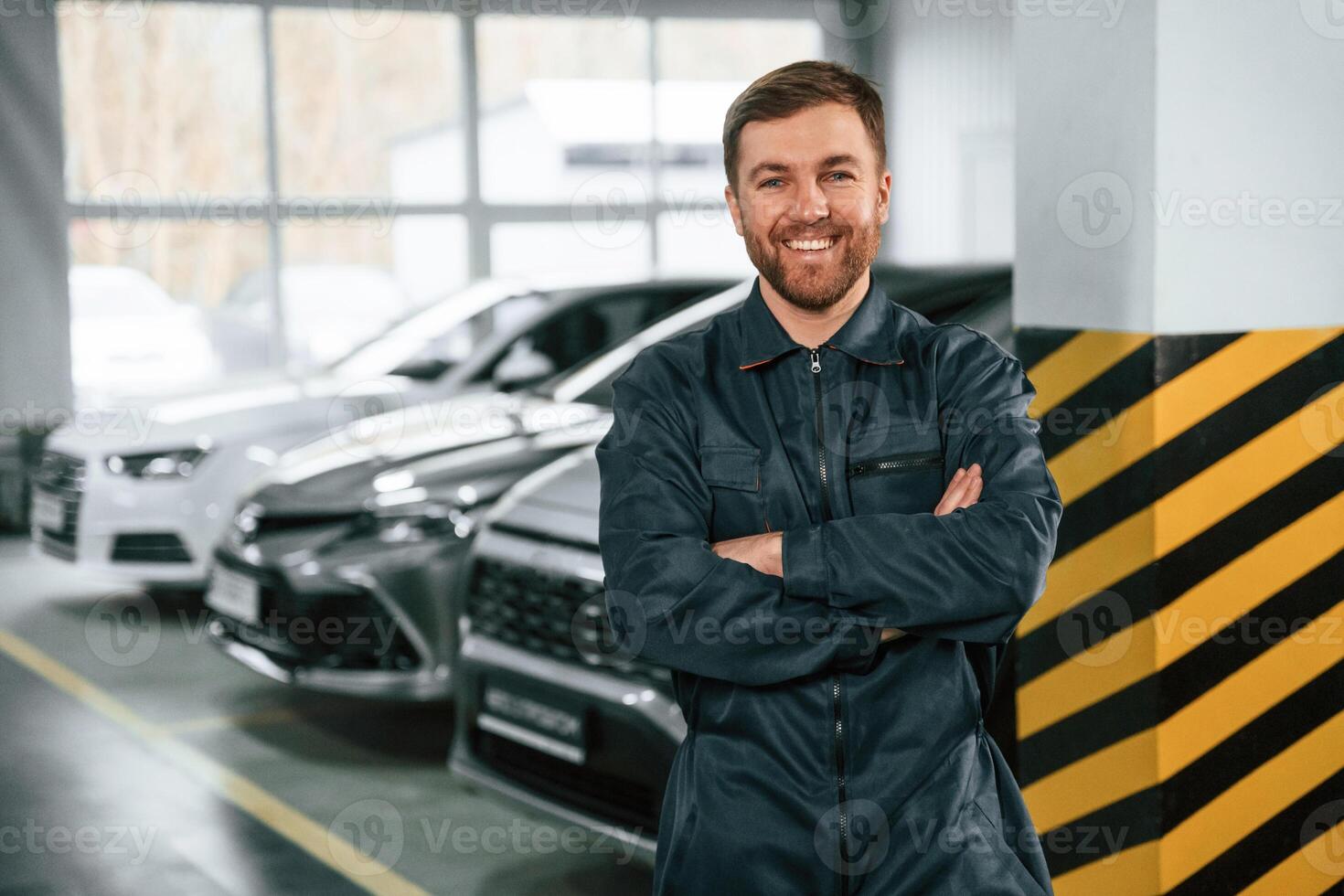 Wiping hands. Repairman ,in uniform is standing in the garage with cars photo