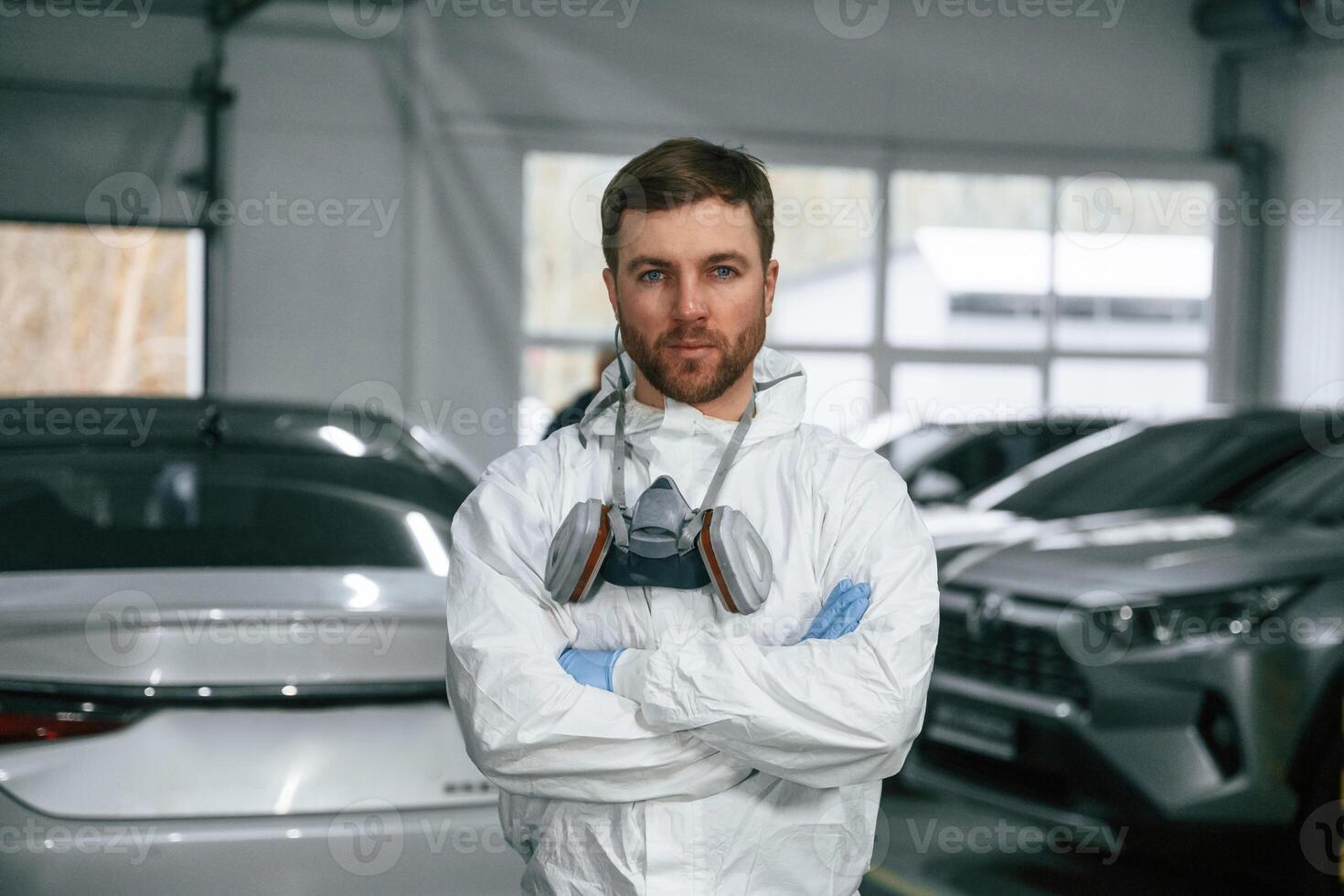 Portrait ,of, professional painter with mask that is standing in the garage with cars photo