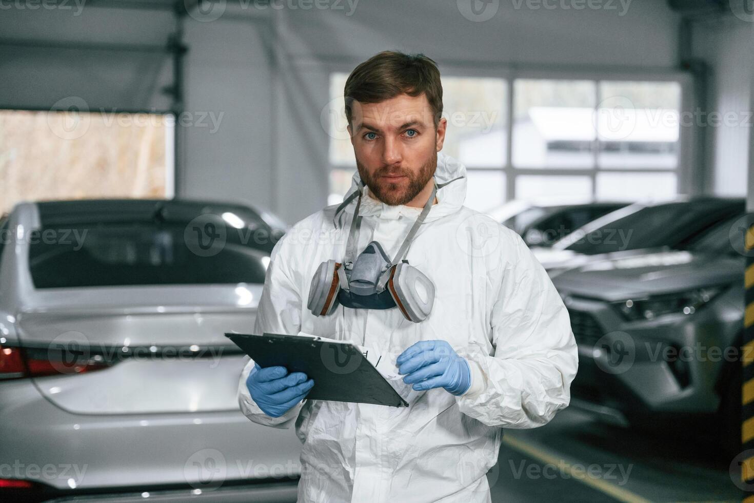 Portrait ,,of car painter that is standing in the garage with documents in hands photo