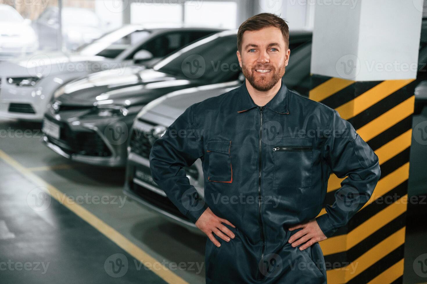 Repairman, in uniform is standing in the garage with cars photo