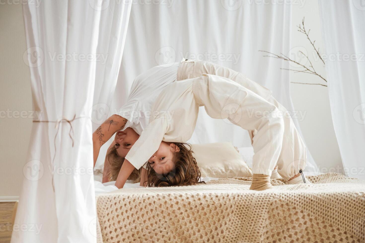 Playing ,in bed, standing on hands and legs. Mother with daughter are at home together photo