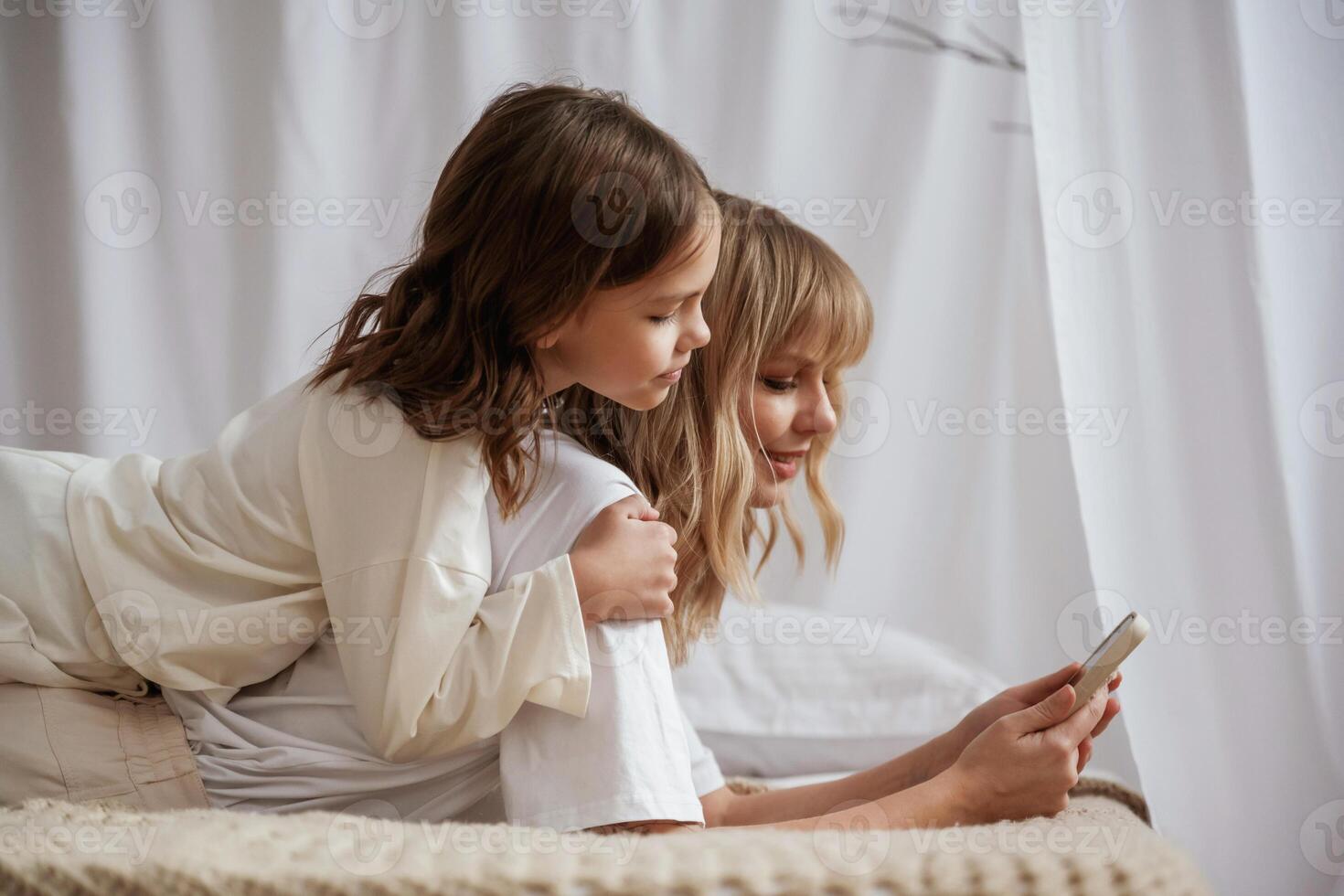 Smartphone ,is in hands.. Mother with daughter are at home together photo