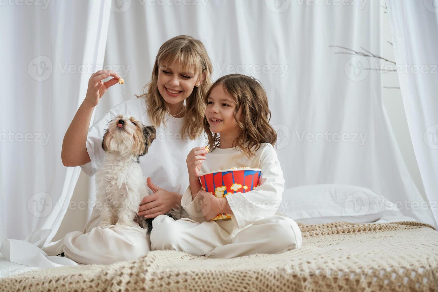 Feeding ,popcorn, do a dog. Mother with daughter are at home together photo