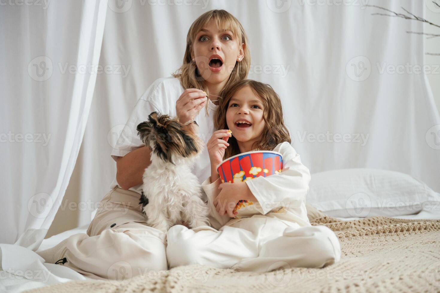 Watching movie, with, popcorn and dog. Mother with daughter are at home together photo