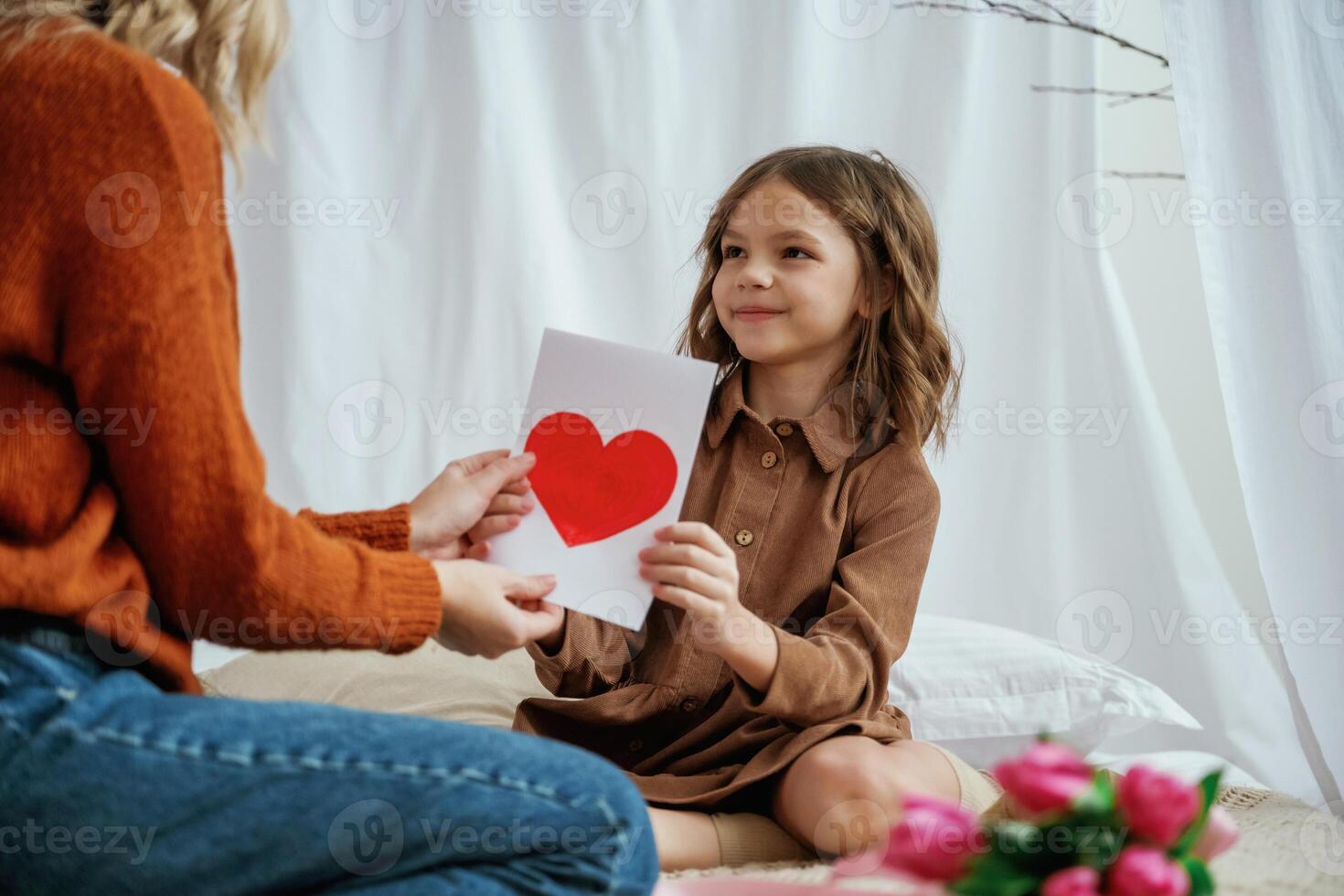 Red ,paper heart shaped present for mother's day. Female parent with daughter is at home photo