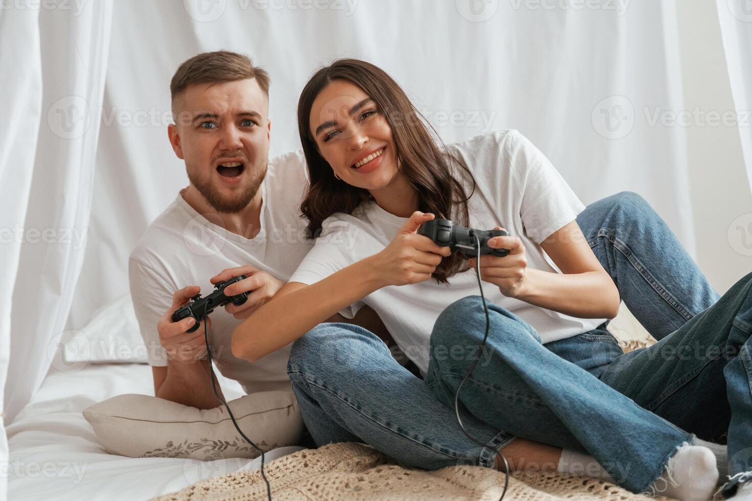 Playing game, with ,,joysticks. Young couple are together at home photo