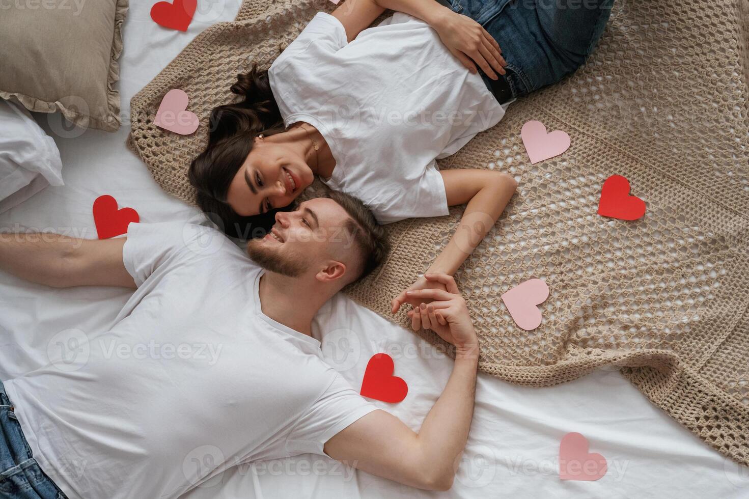 A lot of heart, shaped paper decorations, top view. Young couple are together at home photo