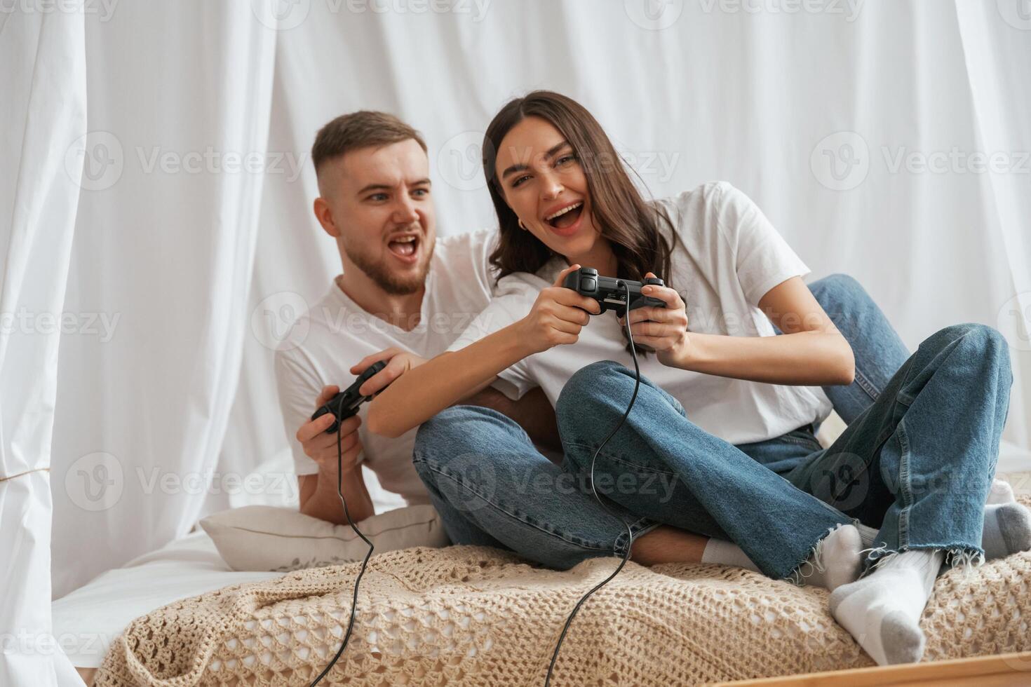 Playing, game with joysticks. Young couple are together at home photo