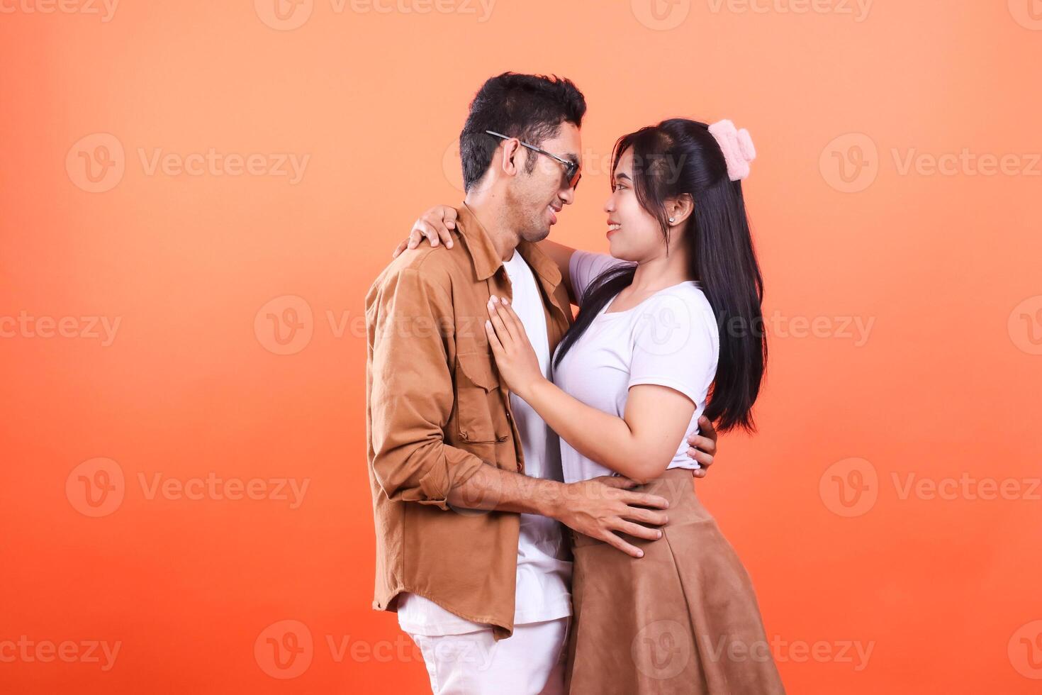 A man and a woman embrace looking at each other isolated on an orange background photo