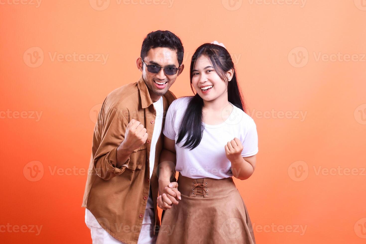 a pair of adult lovers happy expression success where the man stands and the woman faces the camera romantically. isolated on orange background photo