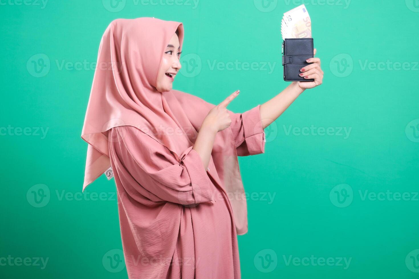 Smiling Muslim woman showing wallet full of cash is happy, isola photo