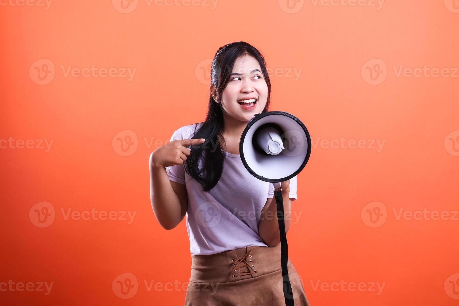 Young Woman with Megaphone on Orange Background Announcing Something Exciting photo