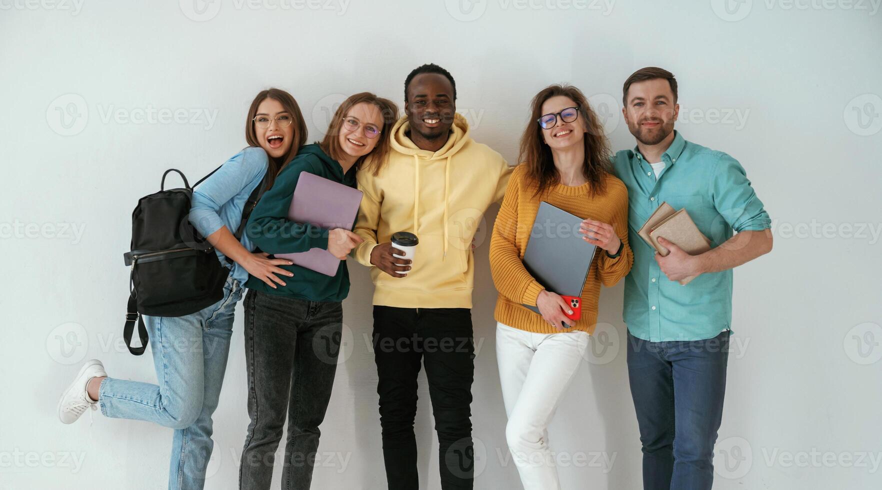 Smiling, looking forward. Group of young people are standing against white background photo