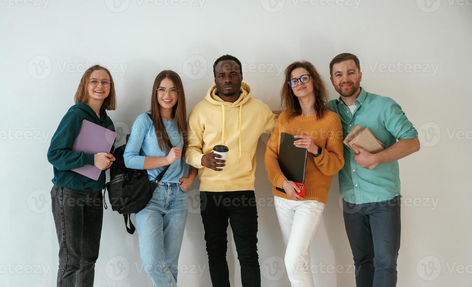 Holding ,notepads, and coffee cup. Group of young people are standing against white background photo