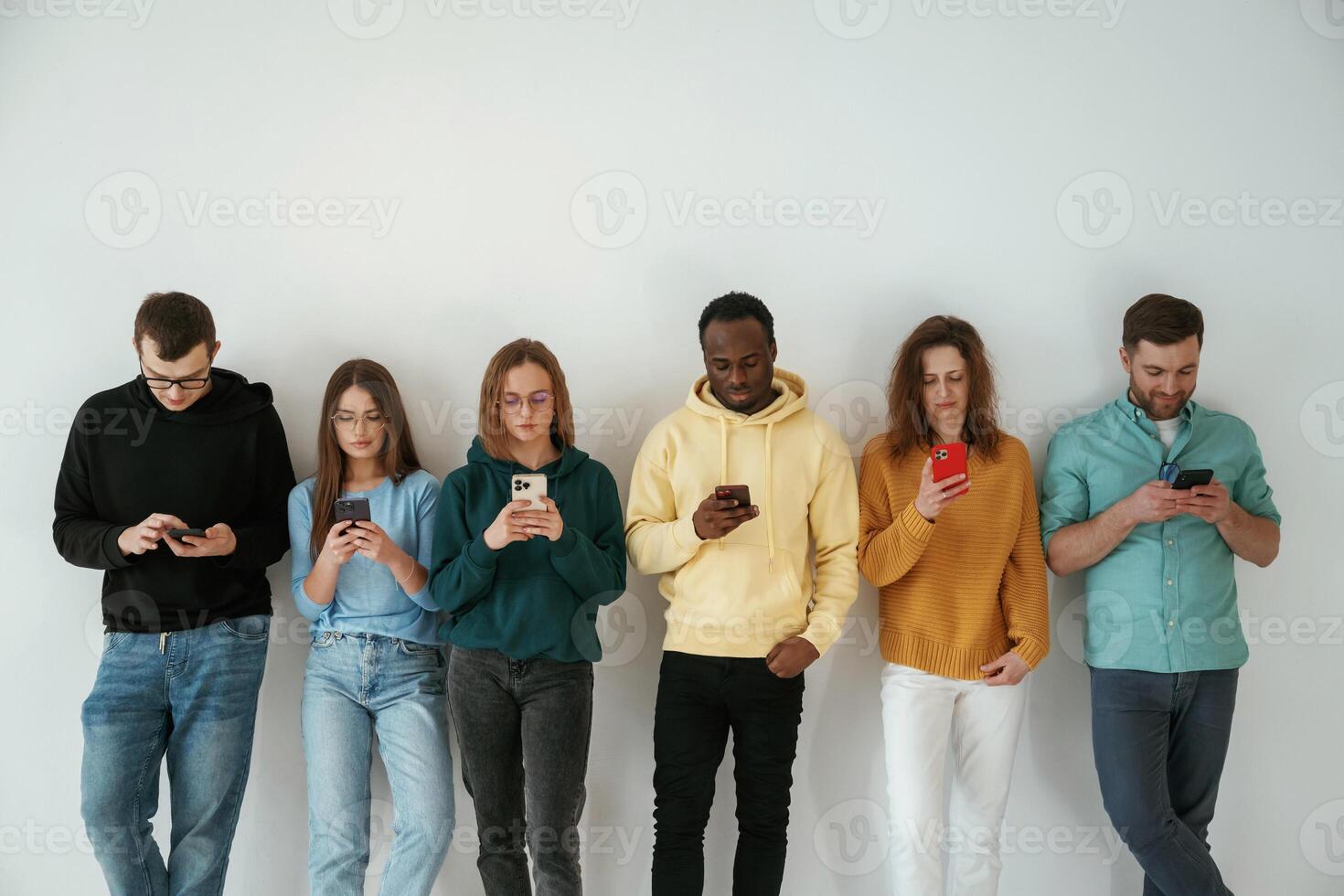 Busy by, using smartphones. Group of young people are standing against white background photo