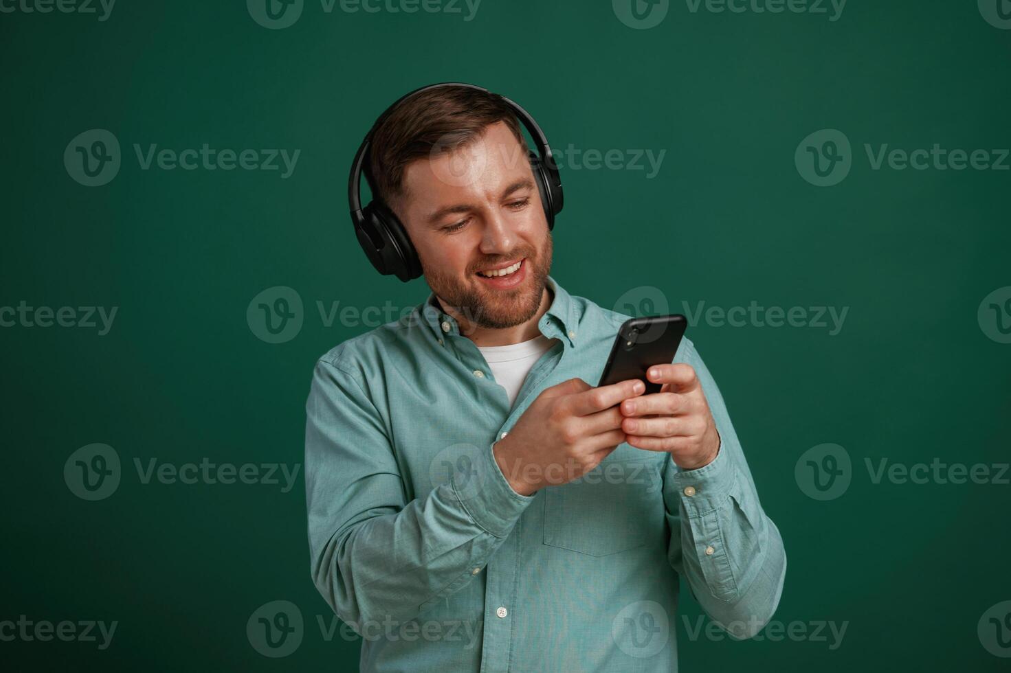 Black smartphone in hands., Man, is standing against background in the studio photo