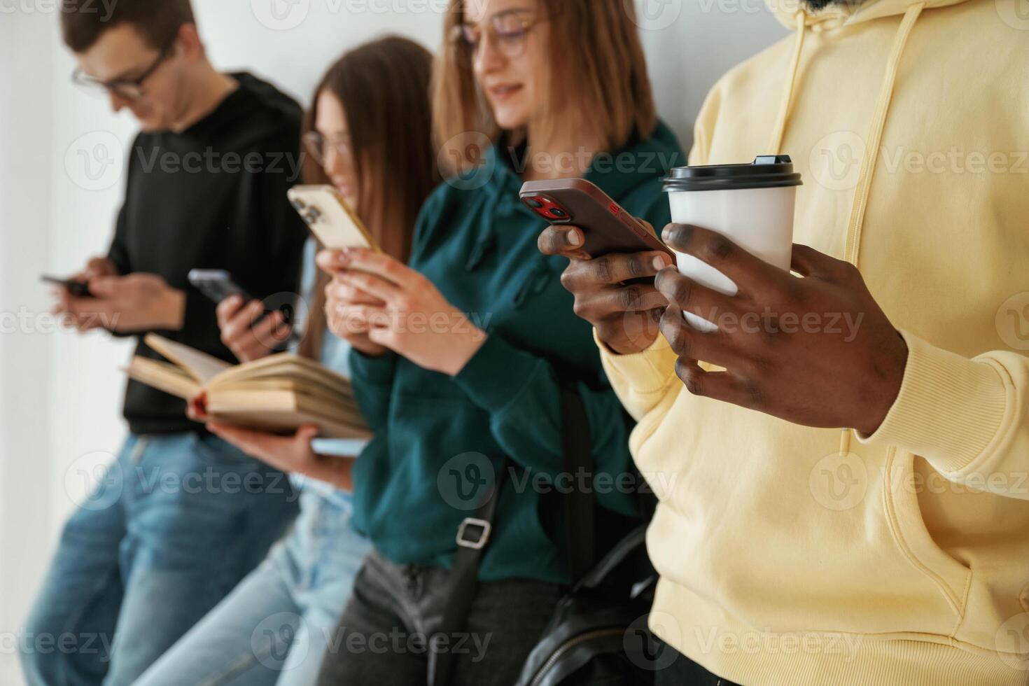Busy by using smartphones.. Group of young people are standing against white background photo
