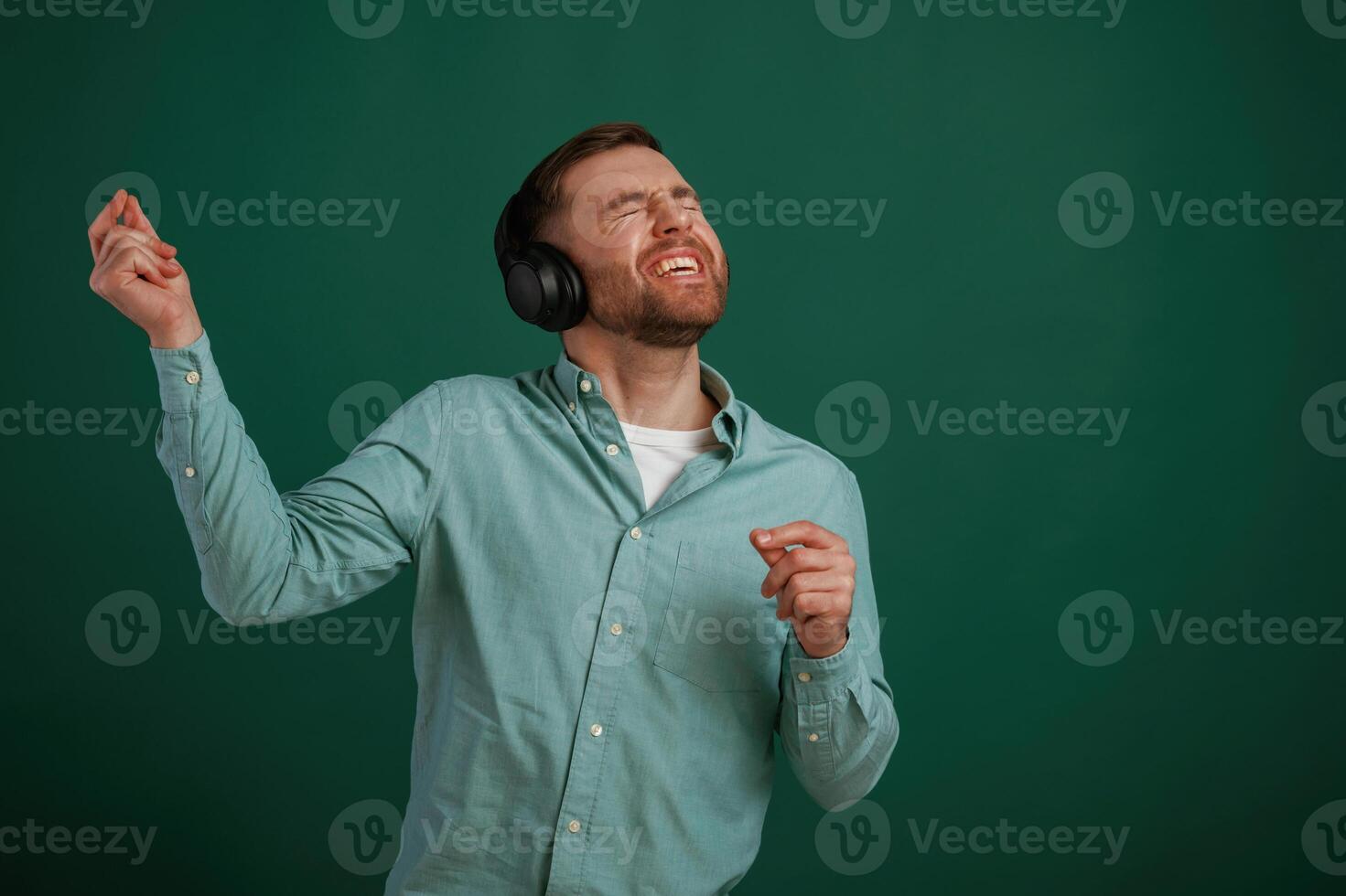 Smiling, enjoying music. Man is standing, against background in the studio photo